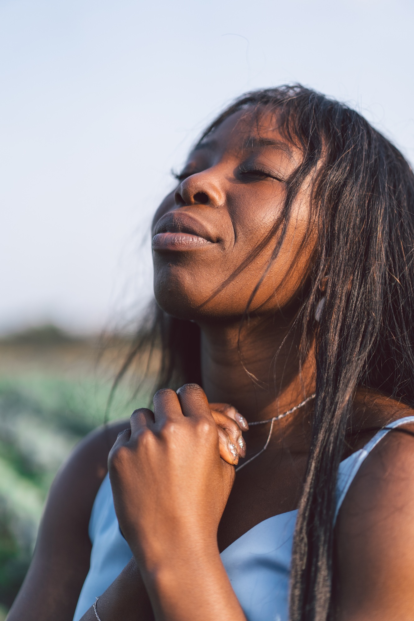 Afro Girl closed her eyes, praying in a outdoors. Hands folded in prayer concept for faith